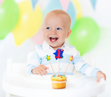 little boy blowing out candle for first birthday